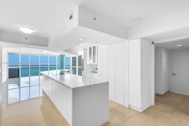a large kitchen with kitchen island a sink and a refrigerator