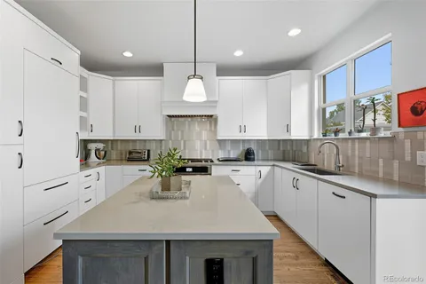 a kitchen with kitchen island granite countertop a sink cabinets and wooden floor