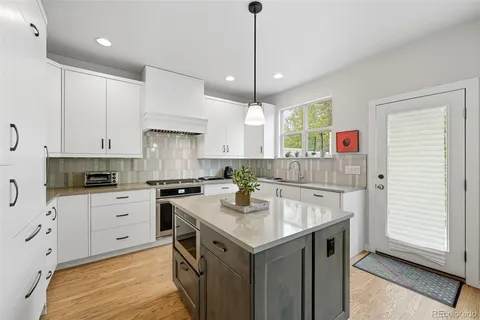 a kitchen with a sink a stove a refrigerator and white cabinets