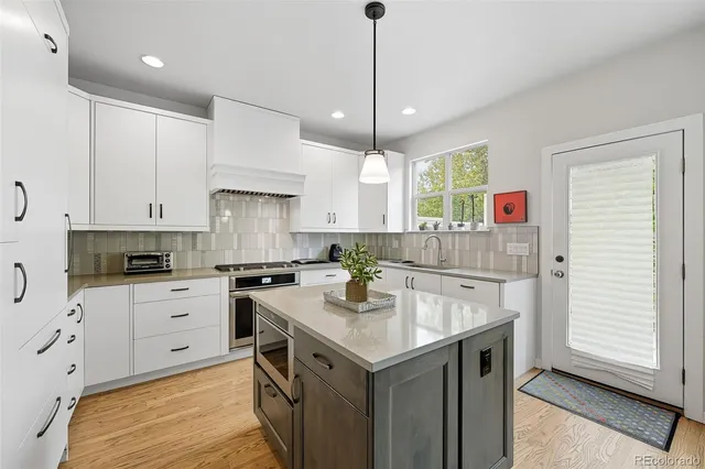 a kitchen with a sink a stove a refrigerator and white cabinets