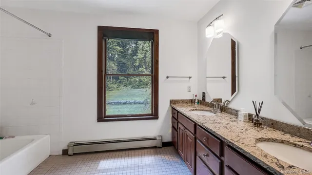a bathroom with a granite countertop sink and a window