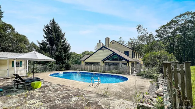 a view of swimming pool with lawn chairs under an umbrella