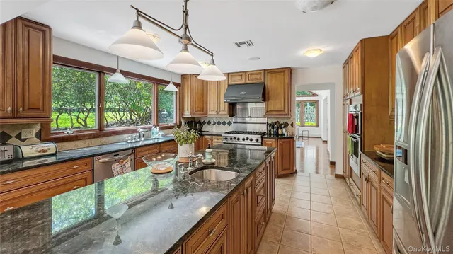 a kitchen with stainless steel appliances granite countertop a sink a stove and a refrigerator