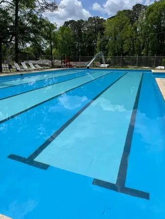 a view of yard with swimming pool and trees in the background
