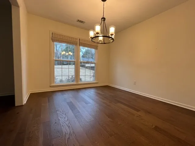 a view of an empty room with wooden floor fireplace and a window