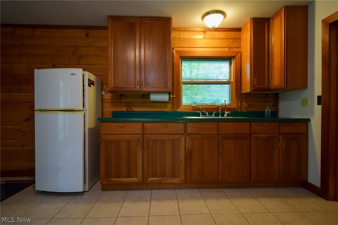 60404 Pigeon Point Road Barnesville, OH 43713 - Photo 3 of 18 Kitchen featuring wooden walls, white fridge, sink, and light tile flooring