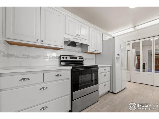 a kitchen with stainless steel appliances granite countertop white cabinets stove and a window