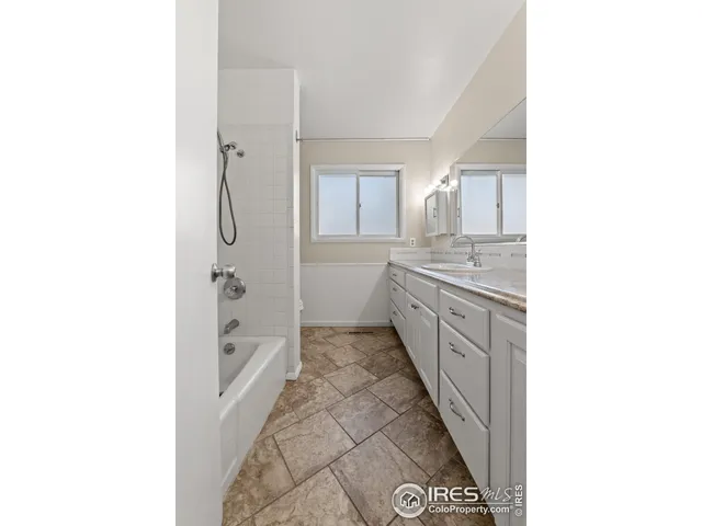 a bathroom with a granite countertop sink a mirror and a bathtub