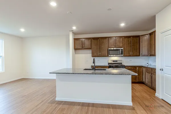 a kitchen with stainless steel appliances granite countertop a sink a stove a refrigerator cabinets and wooden floor