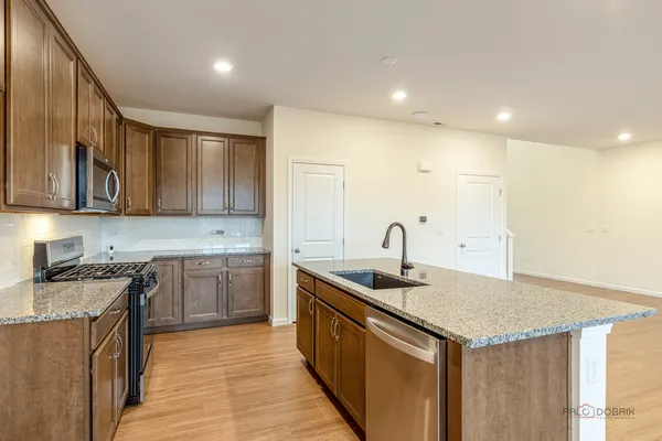 a kitchen with a sink dishwasher a stove and a refrigerator with wooden floor