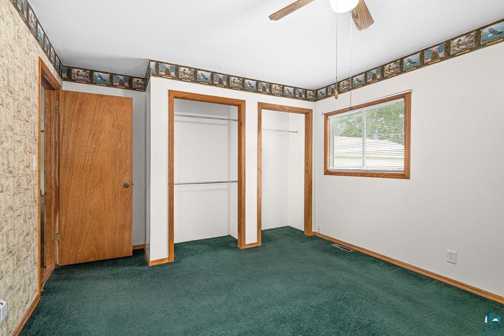 27 James Road Silver Bay, MN 55614 - Photo 13 of 25 Unfurnished bedroom with dark carpet, multiple closets, and ceiling fan