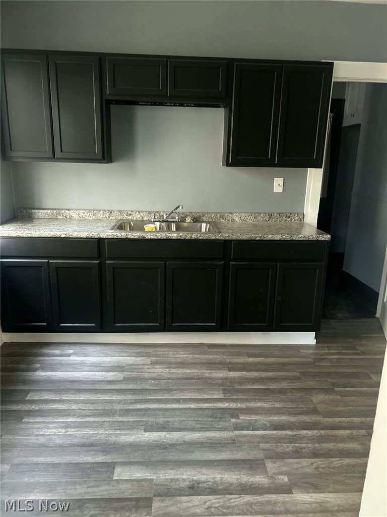 1069 Carlyon Road East Cleveland, OH 44112 - Photo 6 of 25 Kitchen featuring dark cabinetry, light-toned countertops, a stainless steel sink, and wood-finish flooring
