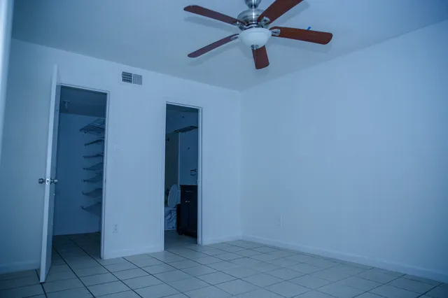 an empty room with windows and fan