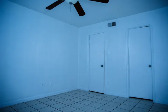 an empty room with closet and a ceiling fan