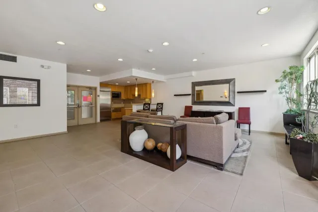 a large living room with stainless steel appliances kitchen island granite countertop a large window and a couch