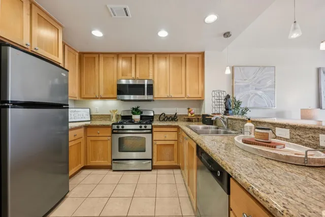 a kitchen with stainless steel appliances granite countertop a sink a stove and a refrigerator