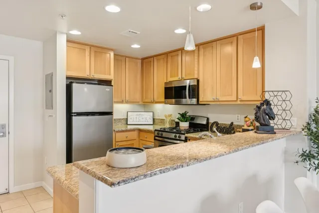 a kitchen with granite countertop kitchen island stainless steel appliances a refrigerator a sink a stove a microwave a center island and furniture
