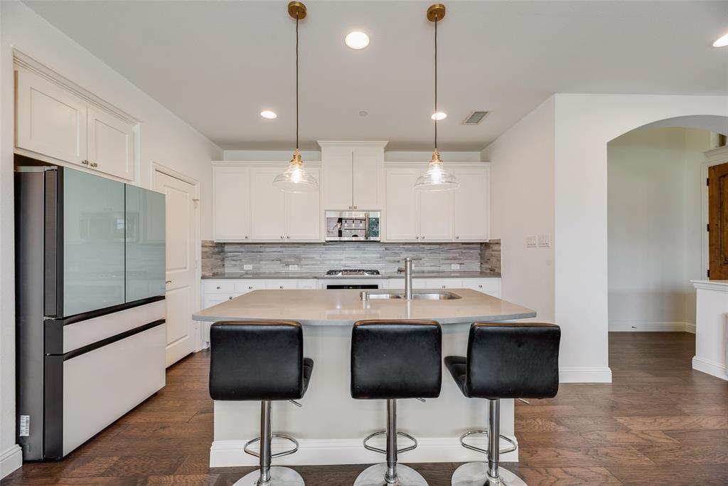 4670 I Rhett Lane, Unit I Carrollton, TX 75010 - Photo 12 of 31 White shaker cabinetry, light-toned countertops, tile backsplash, and dark wood-finish flooring