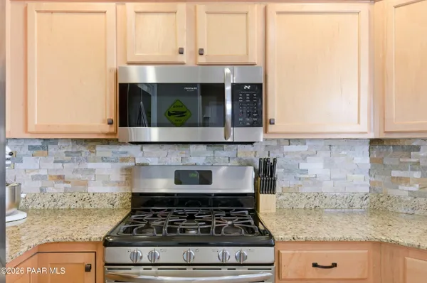 a kitchen with granite countertop a stove a sink and white cabinets