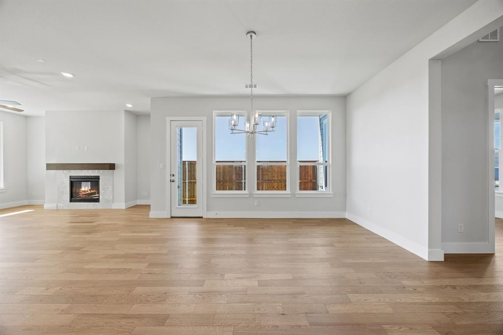 505 Callum Parkway Celina, TX 75009 - Photo 12 of 34 an empty room with wooden floor fireplace and windows