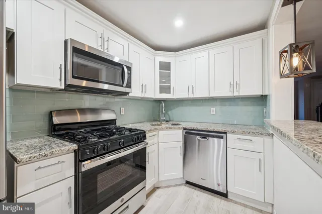 a kitchen with white cabinets and stainless steel appliances