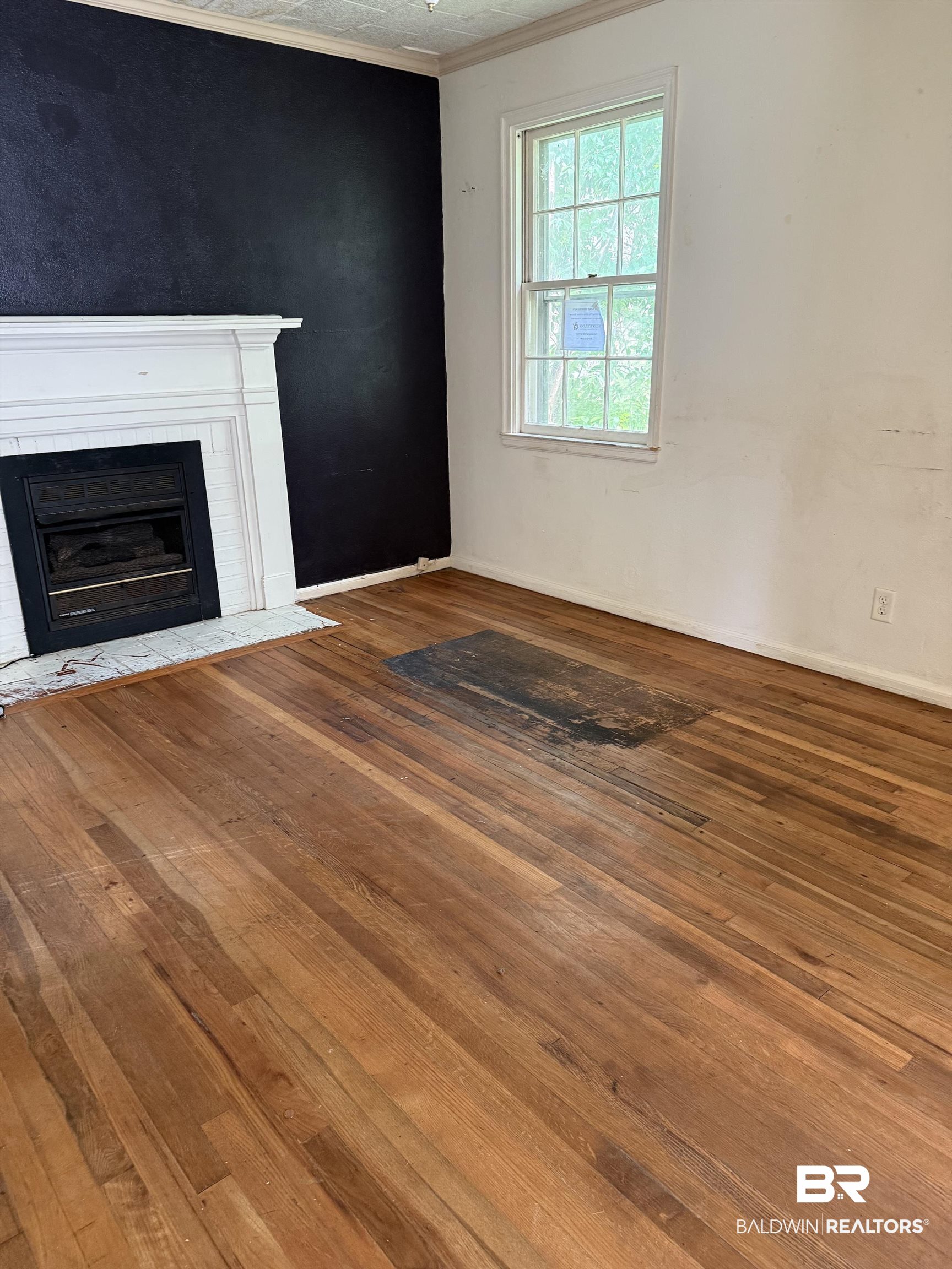 502 East Myrtle Avenue Foley, AL 36535 - Photo 2 of 9 Unfurnished living room with hardwood / wood-style flooring, ornamental molding, and a fireplace with flush hearth