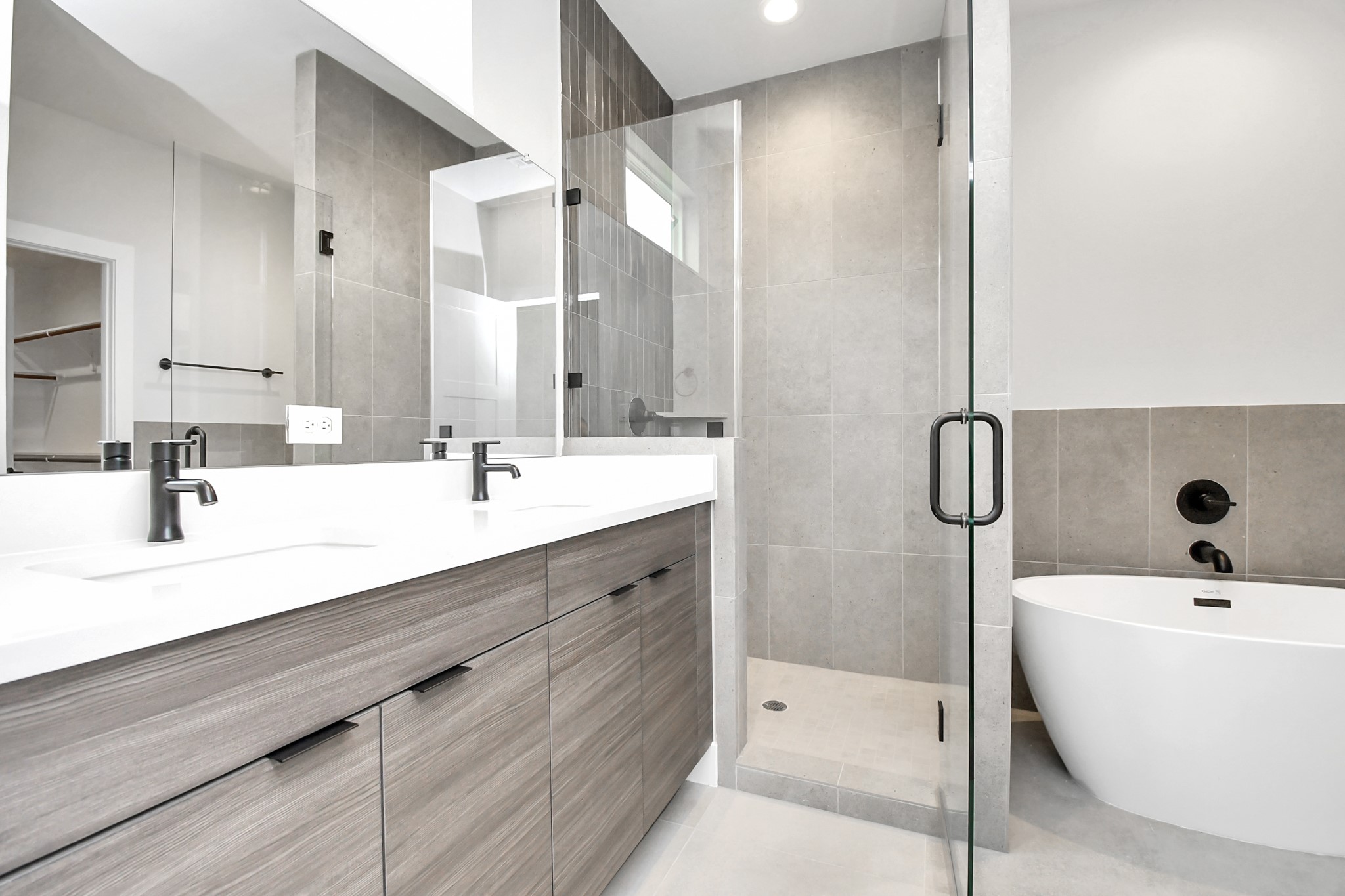 313 Charlock Street Houston, TX 77022 - Photo 20 of 34 This modern bathroom features a spacious glass-enclosed shower, a sleek freestanding bathtub, and a double vanity with contemporary fixtures and ample storage. Neutral tones and clean lines create a serene, elegant atmosphere.