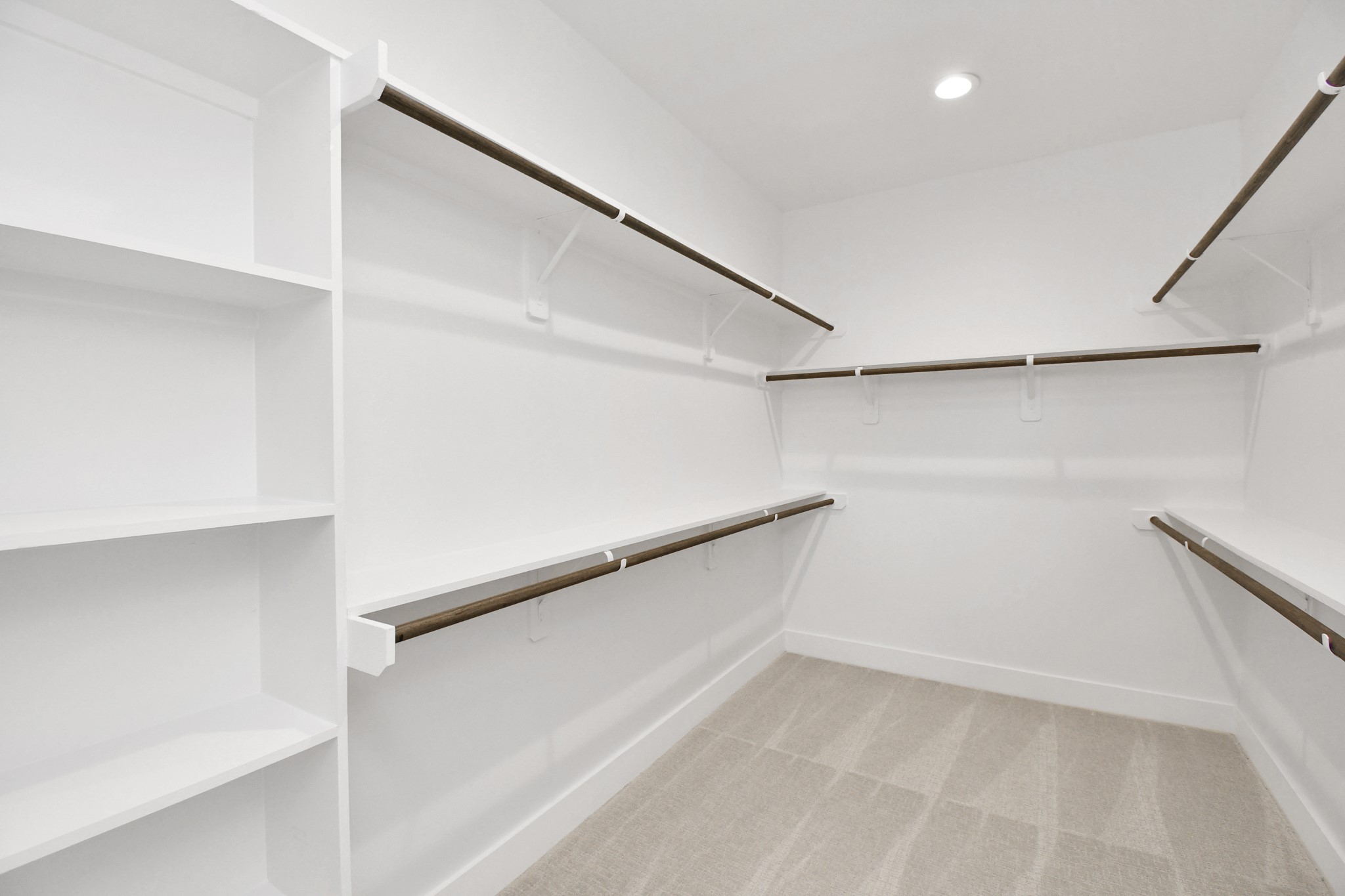 313 Charlock Street Houston, TX 77022 - Photo 22 of 34 This photo shows a spacious, well-lit walk-in closet with ample shelving and hanging space, featuring a clean, modern design with white walls and carpeted flooring.