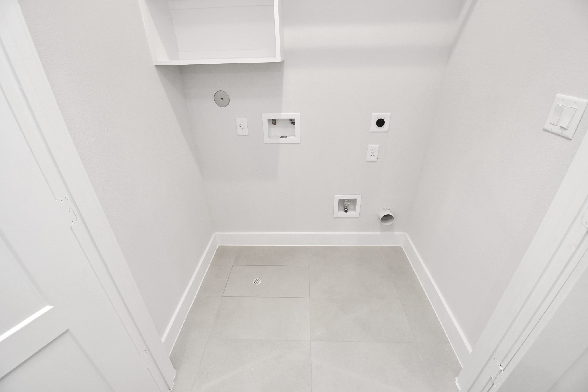 313 Charlock Street Houston, TX 77022 - Photo 23 of 34 This photo shows a laundry room with hookups for a washer and dryer. It features light-colored walls, tile flooring, and a small shelf for storage.