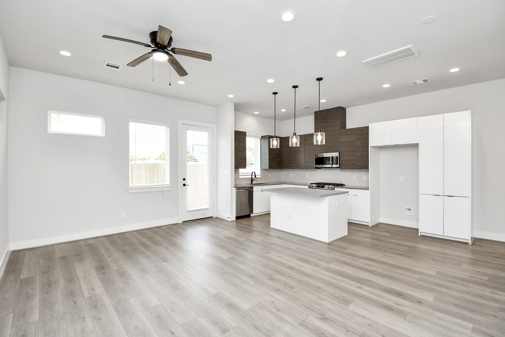 313 Charlock Street Houston, TX 77022 - Photo 5 of 34 This modern, open-concept kitchen and living area features sleek cabinetry, stainless steel appliances, and a central island. The space is bright with natural light from multiple windows, and includes recessed lighting and a ceiling fan for comfort.