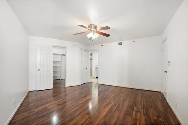 a view of a room with wooden floor and a ceiling fan