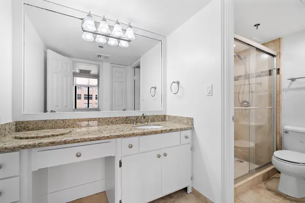 a bathroom with a granite countertop sink a toilet and shower