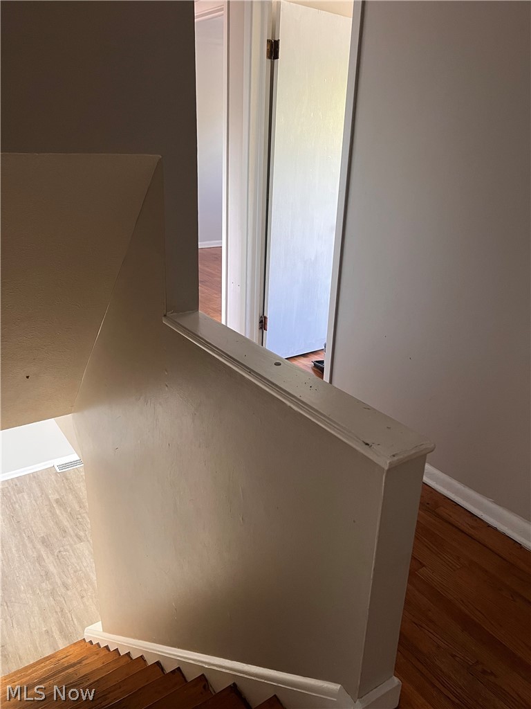 16350 Rockside Road Maple Heights, OH 44137 - Photo 17 of 34 Staircase with wood-finish treads and risers, painted balustrade, and a doorway opening to a room with wood-finish flooring