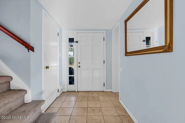 a view of an empty room with wooden floor and a bathroom