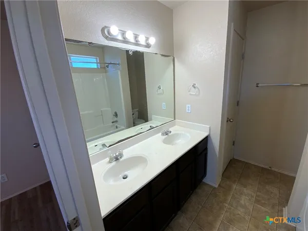 a bathroom with a double vanity sink and mirror with shower
