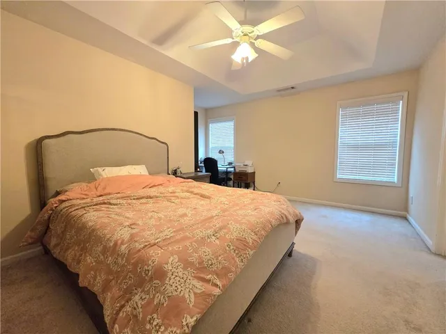 a large bed sitting in a bedroom next to a window and a chandelier