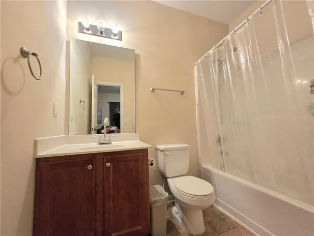 a bathroom with a granite countertop toilet sink and mirror