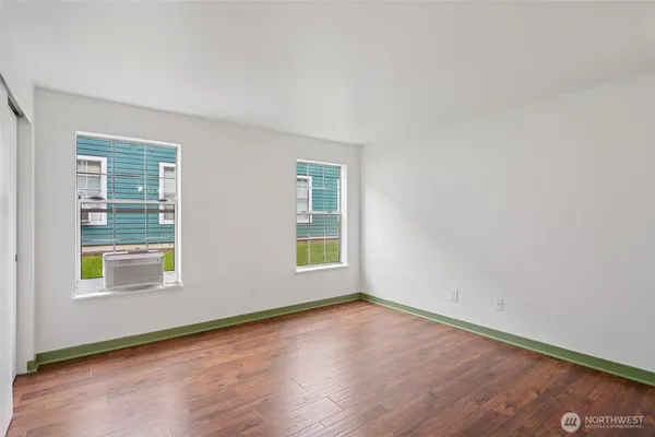 an empty room with wooden floor and windows