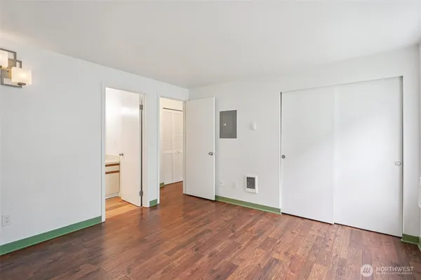 a view of an empty room with wooden floor and closet