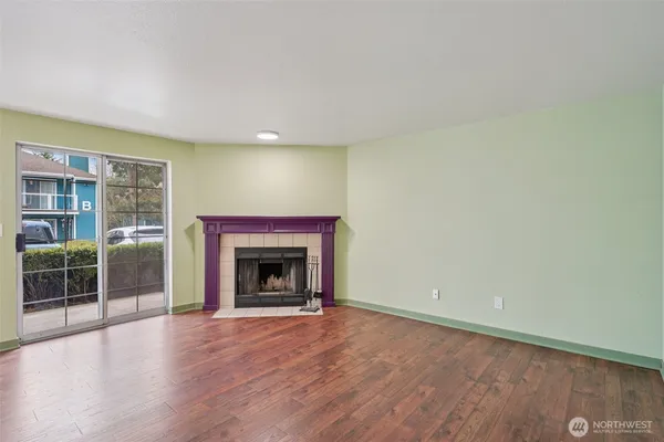 an empty room with wooden floor fireplace and windows