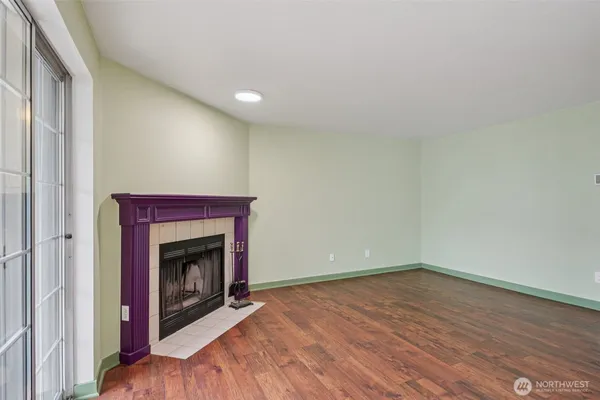 a view of an empty room with wooden floor and a fireplace