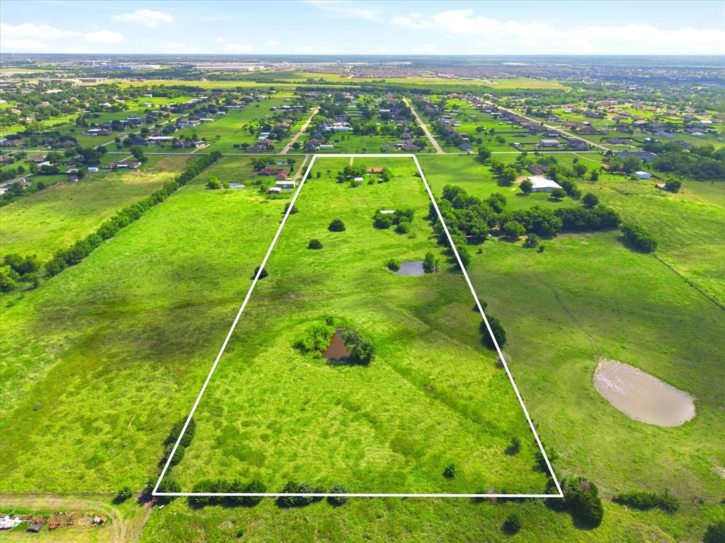 11749 Windy Lane Forney, TX 75126 - Photo 1 of 8 Expansive land parcel featuring a verdant landscape, multiple water features, scattered mature trees, and a distant residential area