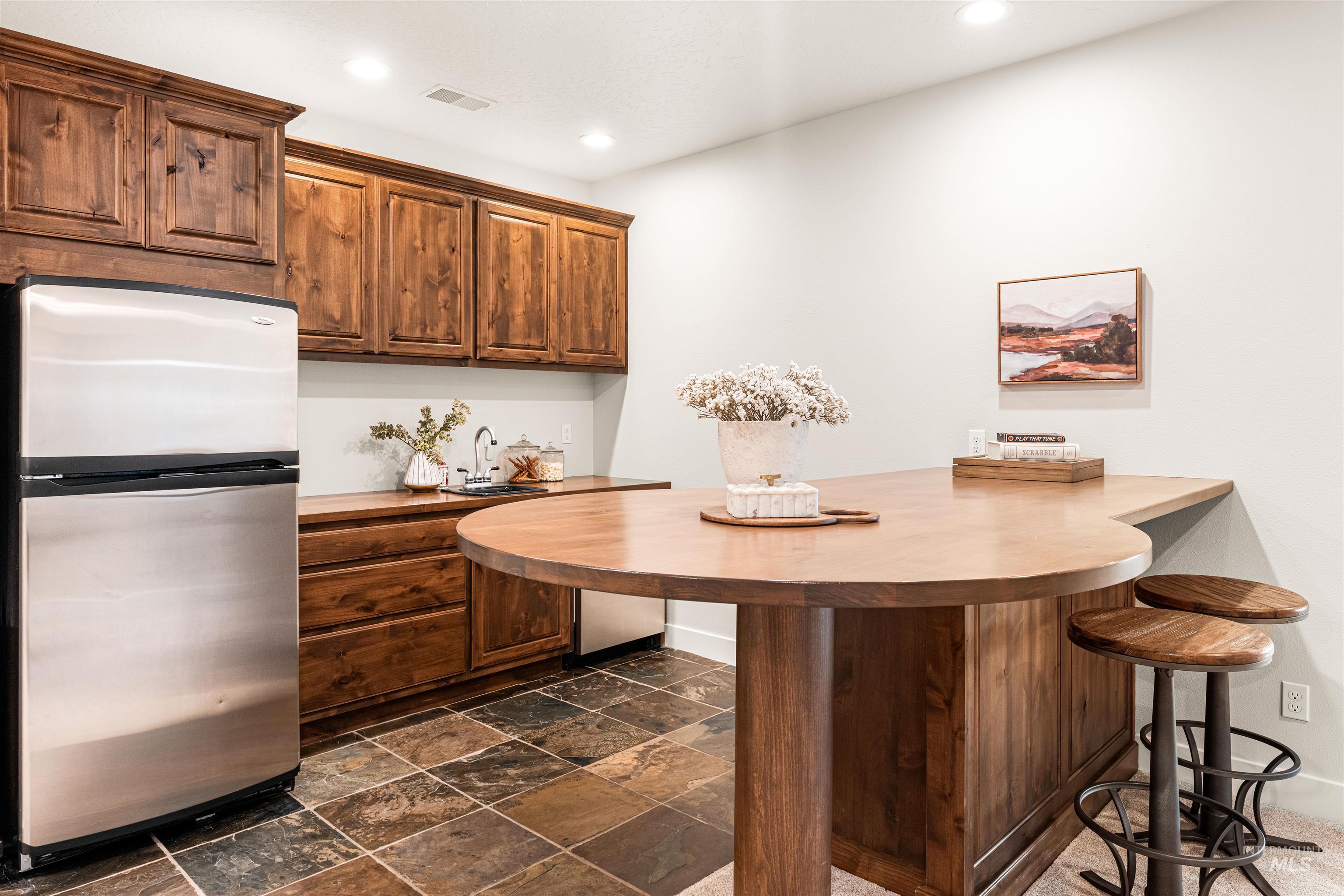 4262 South Rustler Lane Meridian, ID 83642 - Photo 35 of 50 Kitchen with freestanding refrigerator, a peninsula, a breakfast bar, stone tile floors, and recessed lighting