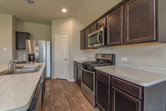 a kitchen with stainless steel appliances granite countertop a sink stove microwave and refrigerator