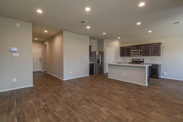 a view of kitchen with kitchen island granite countertop stainless steel appliances refrigerator and cabinets