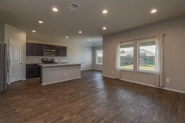 a view of kitchen with kitchen island a sink wooden floor and stainless steel appliances