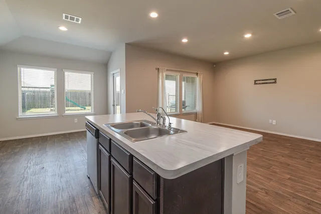 an open kitchen with a sink a stove and wooden floor