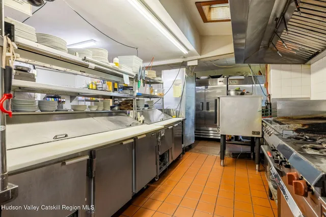 a kitchen with stainless steel appliances granite countertop a sink a stove a cabinets a dining table and chairs