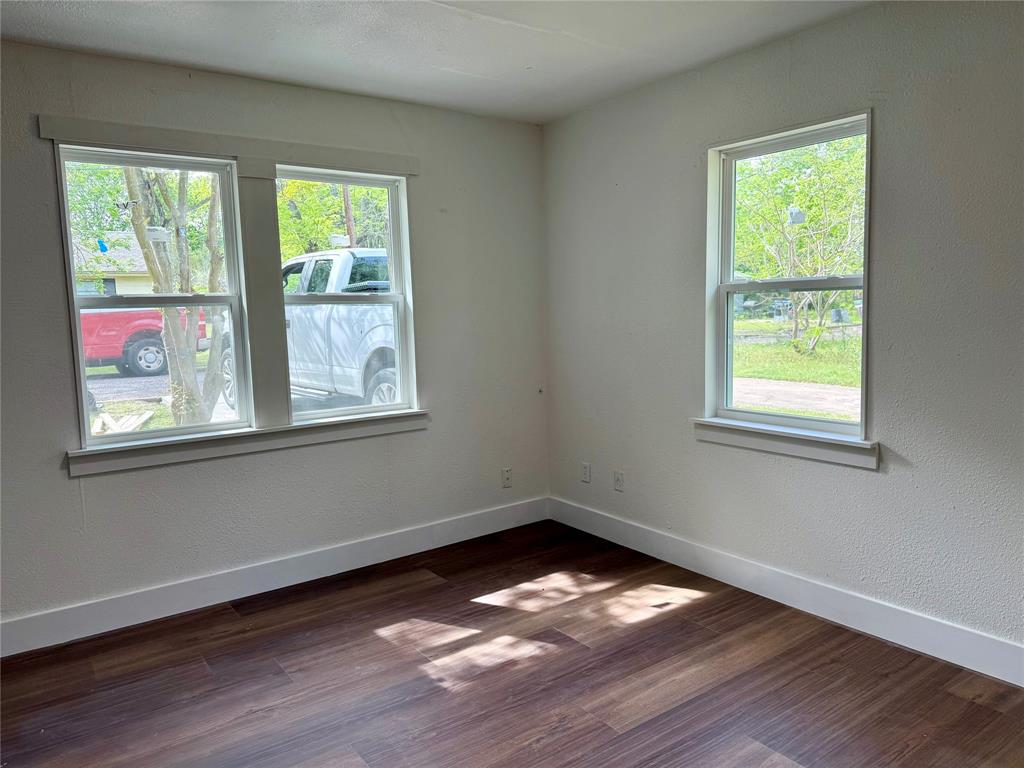 1114 Blackburn Street Commerce, TX 75428 - Photo 7 of 20 a view of an empty room with wooden floor and a window