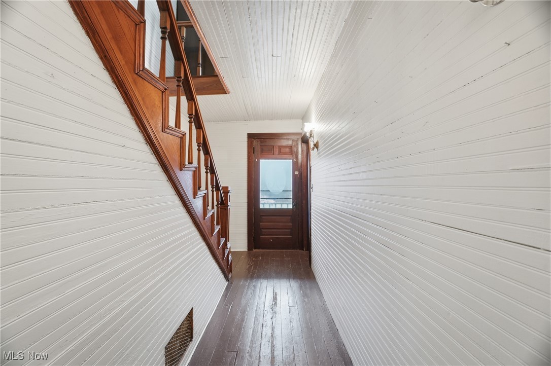 8045 Veto Road Belpre, OH 45714 - Photo 24 of 50 Hallway with stairs, wood walls, and dark wood-style flooring